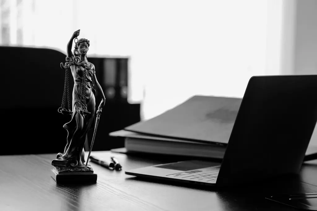 Justitia-Statue neben einem geöffneten Laptop