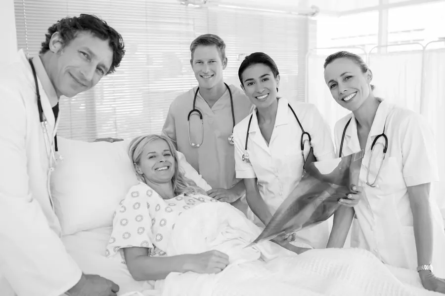 Frau im Krankenhausbett mit vier Ärzten
